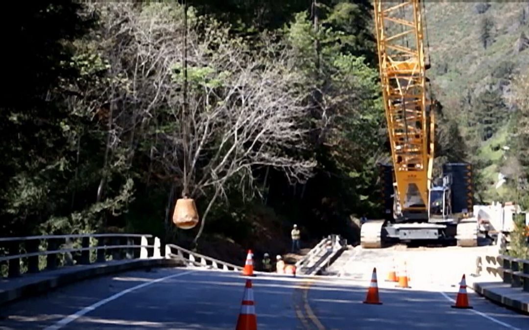 Liebherr crawler with wrecking ball trying  to bringing down condemned California Bridge in Big Sur